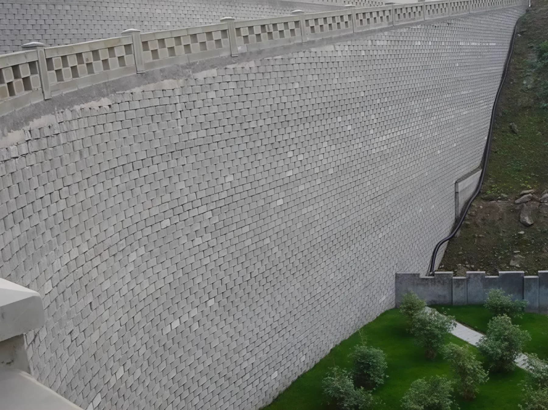 Completed modular block retaining wall following a curve, with planting above the coping.