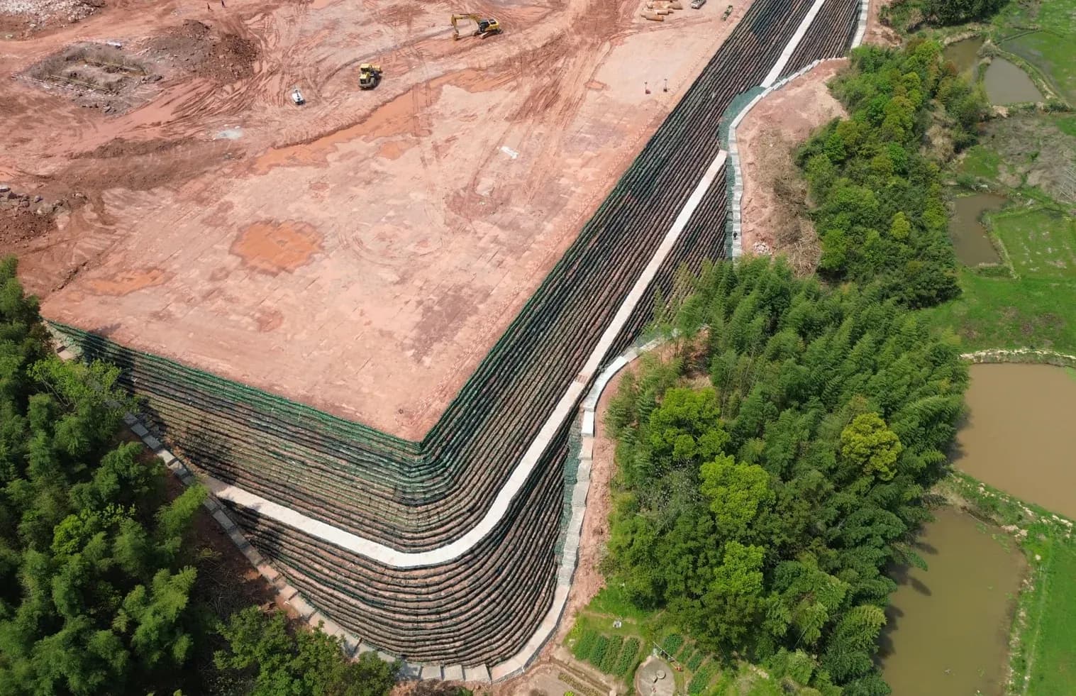 Aerial view of a level working platform carried on multi-tier reinforced soil terraces.